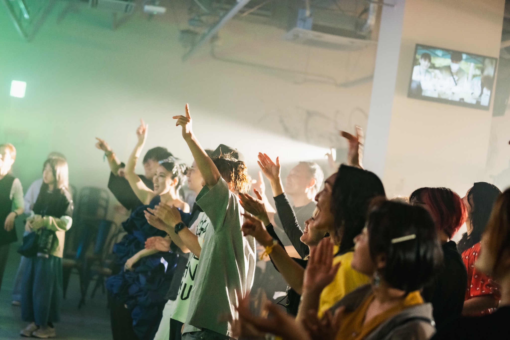 WEAVE!の会場で、音楽に合わせて手を上げる観客たち